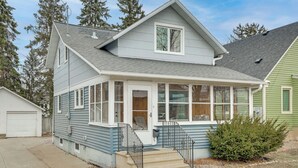 A two-story house with a covered porch, a front door, and a small front yard. - Walk to Dtwn: Rochester Home, Private Deck + Yard! (Rochester)