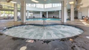 A large indoor swimming pool with a hot tub, surrounded by lounge chairs and a high ceiling with skylights. - Steps to Beach!  Couple or small family retreat! (Gulf Shores)