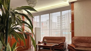 A spacious living area with a brown leather sofa, a coffee table, and a potted plant.