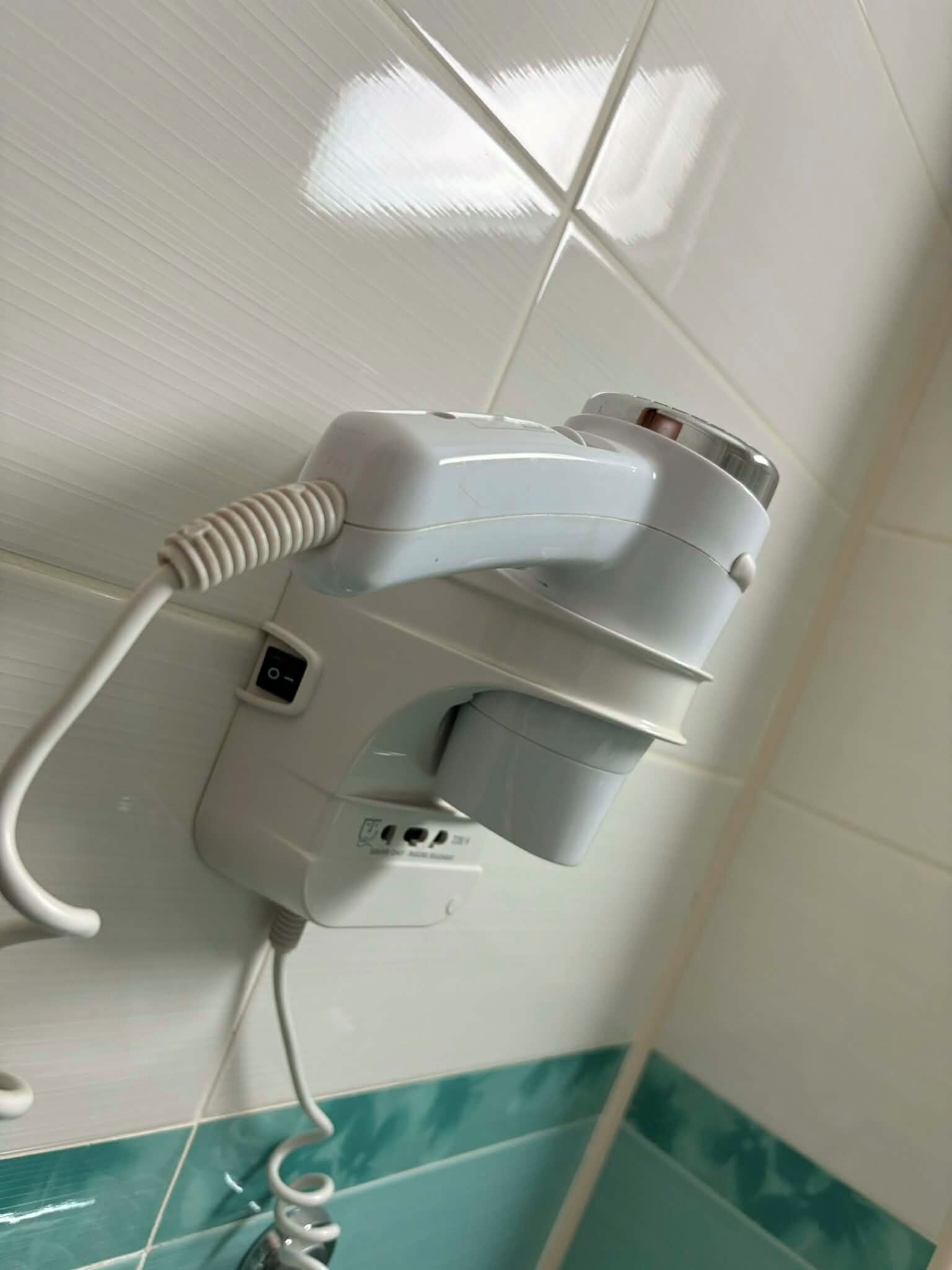 Un sèche-cheveux fixé au mur, équipé d’une prise de courant, d’un port USB et d’un panneau de commande.