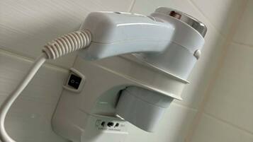 Un sèche-cheveux fixé au mur, équipé d’une prise de courant, d’un port USB et d’un panneau de commande.