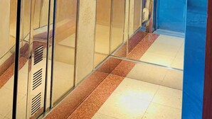 An elevator with glass panels, control buttons, and emergency instructions.