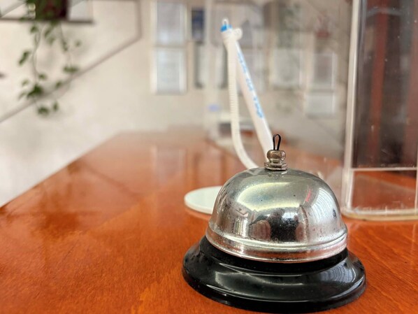 A wooden table with a metallic object on a black base, a toothbrush, and a glass container in the background. - Hotel Emma West Craiova (Craiova)