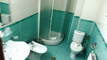A bathroom with a shower, toilet, bidet, and sink.