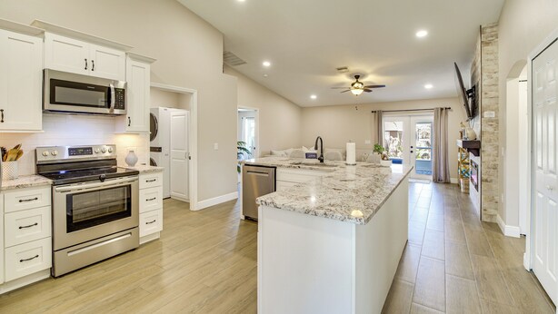 A modern kitchen with white cabinetry, stainless steel appliances, and a large island. - Jump Into Fall at This Cozy Gem w/ Private Pool! (Palm Bay)
