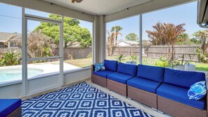 A sunroom with a pool, a blue sofa, and a patterned rug. - Jump Into Fall at This Cozy Gem w/ Private Pool! (Palm Bay)