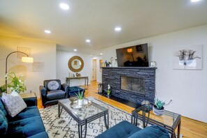 Un salon moderne avec une cheminée en pierre, un ensemble de canapés bleus, une table basse et un miroir décoratif.