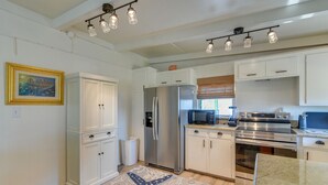 A modern kitchen with white cabinetry, stainless steel appliances, and a starfish-patterned rug. - Steps to Surfside Beach! Ocean-View Texas Retreat (Freeport)
