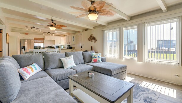 A modern living room with a sectional sofa, a coffee table, and a ceiling fan. - Steps to Surfside Beach! Ocean-View Texas Retreat (Freeport)