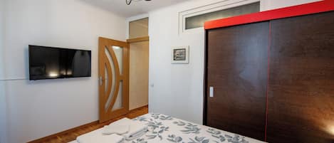 A bedroom with a bed, a TV, a wardrobe, and a door.