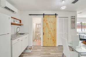 A modern kitchen with a sink, cabinets, and a dining area with a glass table and chairs. - Pool Access! Snowbird Gem in Country Club of Miami (Hialeah)