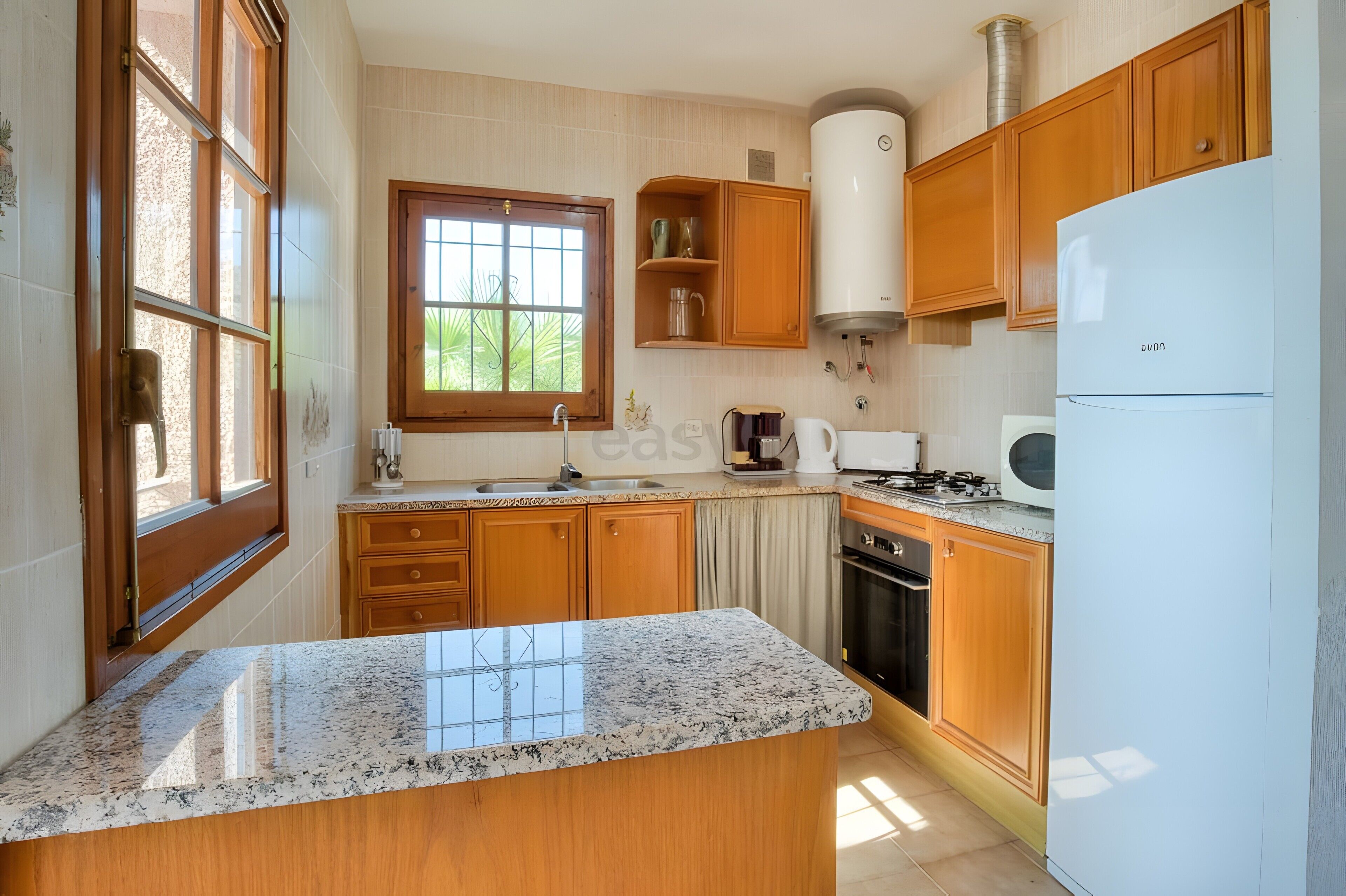 A kitchen with wooden cabinets, a granite countertop, a window, and a built-in stove.
