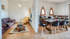 Ein modernes Wohnzimmer mit einer Couch, einem Esstisch mit Stühlen, einer Küchenzeile und einem Fenster mit Blick.