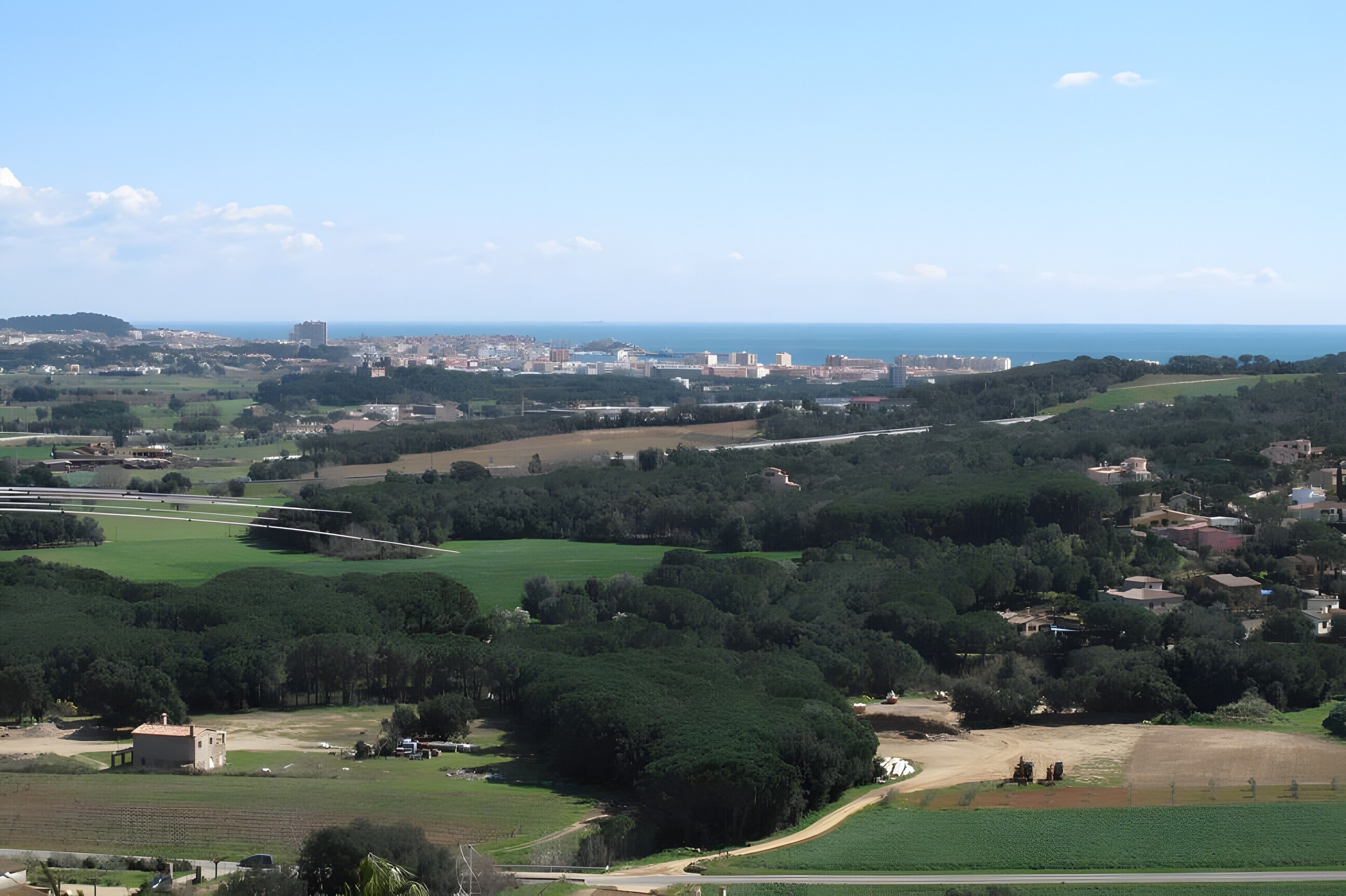 Paisaje rural con campos, árboles y un pueblo distante.