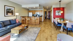 A modern living room with a sofa, coffee table, and a dining area with chairs and a table.