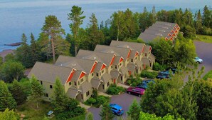 A row of cabins with a view of the ocean, surrounded by trees.