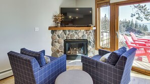 A living room with a stone fireplace, a flat-screen TV, and two blue-patterned sofas.