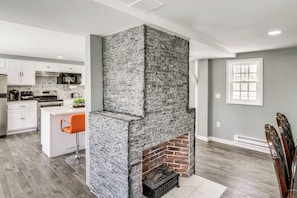 A modern kitchen with white cabinets, a built-in oven, and a stone fireplace. - Indoor Hot Tub & Sauna! Spacious Catskills Home (Cairo)