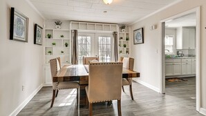 En matplats med ett träbord och stolar, en inbyggd hylla med växter och utsikt mot köket.