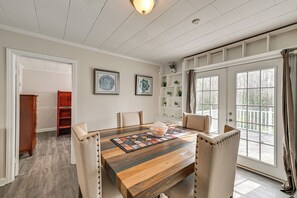 A dining area with a wooden table, cushioned chairs, and a view through large windows. - Family Fun in Gastonia! Home 3 Mi to Downtown (Gastonia)