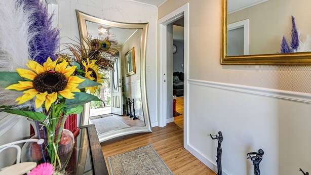 A hallway with a mirror, a vase with sunflowers, and a door leading to another room. - 4 Mi to Hyde Park Village! Modern Escape w/ Yard (Tampa)