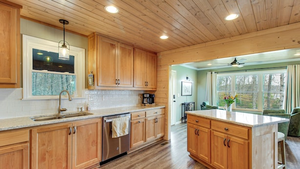 A kitchen with wooden cabinets, a stainless steel dishwasher, and a large island with a sink. - Bring Your Boat! Waterfront Stay on Tims Ford Lake (Estill Springs)