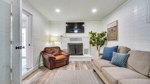 Ein Wohnzimmer mit Kamin, Ledersofa und beiger Couch.