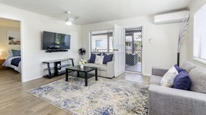 Ein Wohnzimmer mit Flachbildfernseher, Couch, Couchtisch und einem gemusterten Teppich.