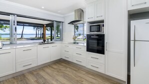 Una cocina moderna con armarios blancos, horno empotrado, microondas y un amplio ventanal con vistas al exterior.