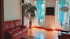 Ein Wohnzimmer mit einem roten Sofa, einem Couchtisch, einer Topfpflanze und einem Fernseher.