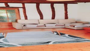 Ein Zimmer mit einer Eckcouch, einem gemusterten Teppich, Holzboden und einem großen Fenster mit Blick.