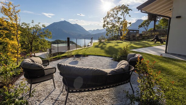 Un patio con mobiliario exterior, vistas a montañas y un lago.