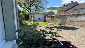 A patio with a green umbrella, two striped chairs, and a potted plant. - Charming and comfortable holiday home in Melay (Melay)