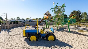A sandy playground with a tractor, climbing structures, and a swing set. - Beachfront Coastal Villa in Renesse for 6 (Renesse)