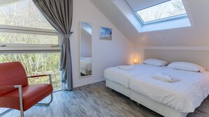 A bedroom with a bed, a chair, a skylight, and a window. - Beachfront Coastal Villa in Renesse for 6 (Renesse)