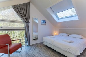 Ein Schlafzimmer mit einem Bett, einem Sessel, einem Oberlicht und einem Fenster.