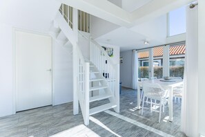 Ein modernes Interieur mit einer weißen Treppe, einem Essbereich mit weißer Möbel und Blick nach draußen.