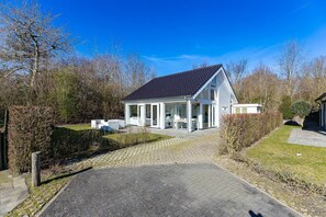 Ein modernes Haus mit überdachter Terrasse, gepflasterter Auffahrt und einem gepflegten Garten.