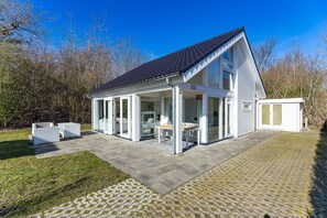 A modern house with a covered patio, a dining area, and a small shed. - Beachfront Coastal Villa in Renesse for 6 (Renesse)
