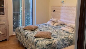 Slaapkamer met een bed, houten vloer, een kledingkast, een raam met uitzicht en een plafond met zichtbare balken.