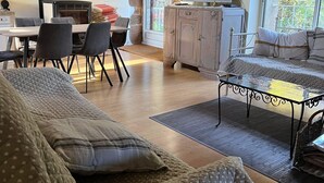 Een gezellige woonkamer met een bank, een eettafel met stoelen, een televisie en uitzicht op het groen.