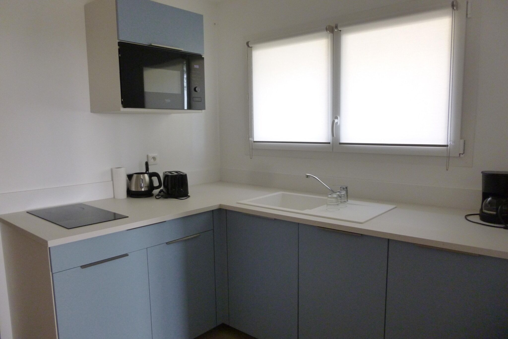 A kitchen with a microwave, toaster, and coffee maker on the counter, a sink, and cabinets.