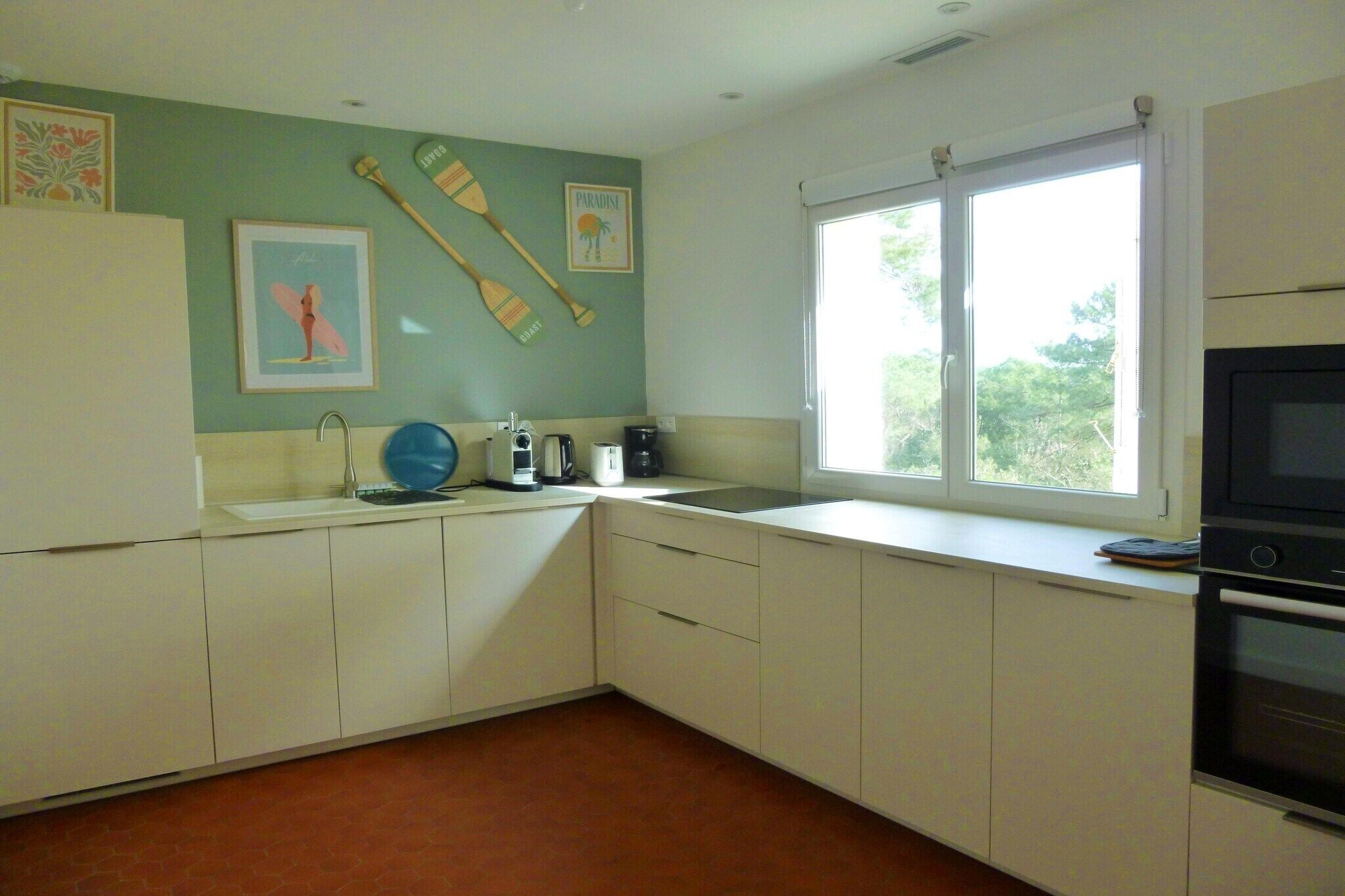 A kitchen with white cabinets, a sink, a stove, and a window.