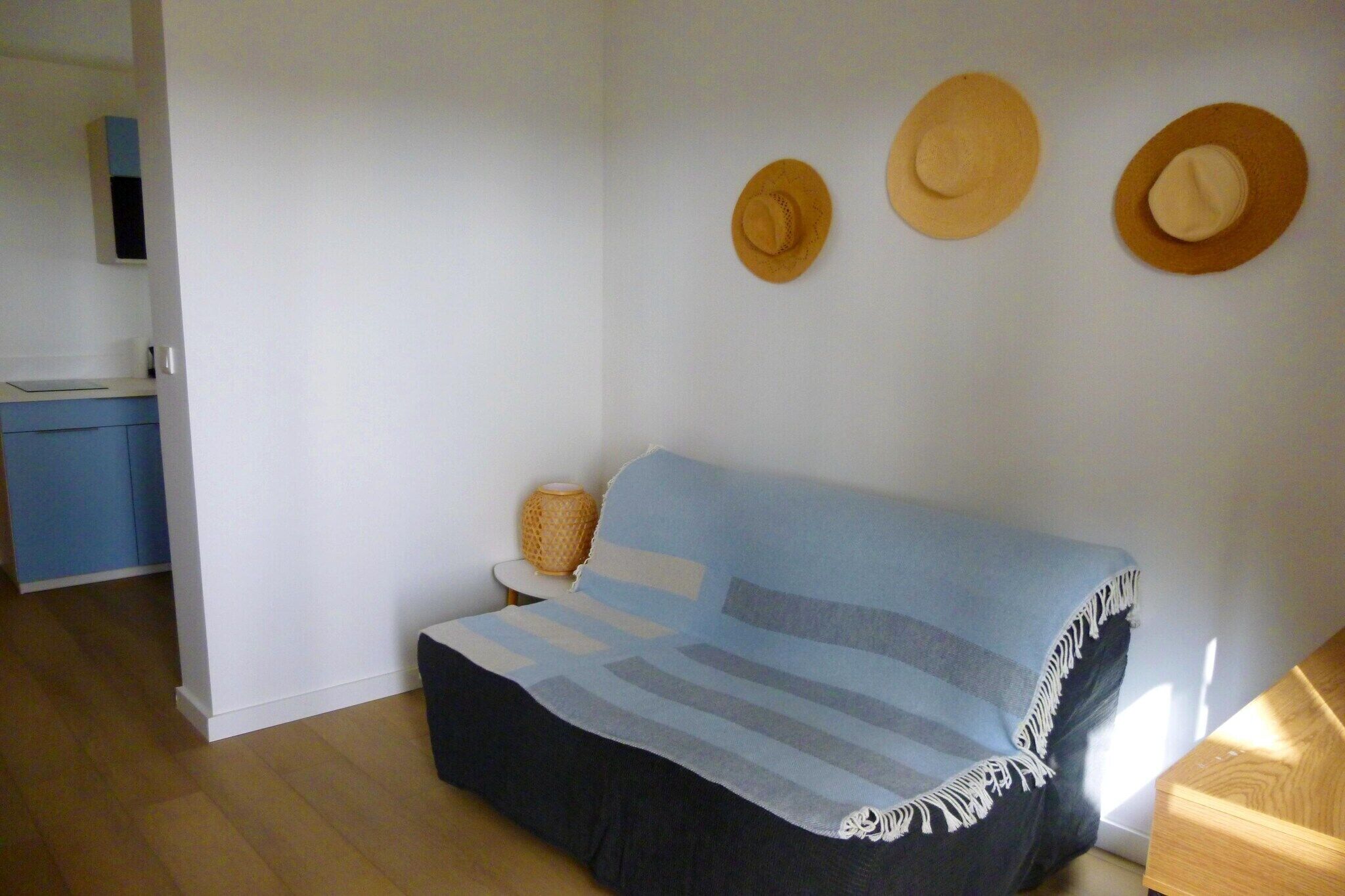 A room with a sofa, a small table, and three hats on the wall.