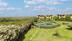 A hotel with multiple yellow buildings, a swimming pool, and a well-maintained garden. - Holiday home with air conditioning and shared pool (Viddalba)