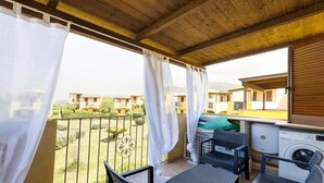 A balcony with a washing machine, a table, and two chairs. - Holiday home with air conditioning and shared pool (Viddalba)