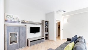 Ein modernes Wohnzimmer mit grauem Sofa, Flachbildfernseher, integriertem Unterhaltungssystem und Holzschrank.