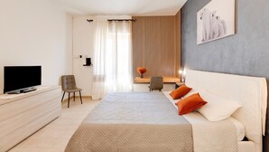 Ein modernes Hotelzimmer mit Bett, Fernseher, Schreibtisch und Stuhl.