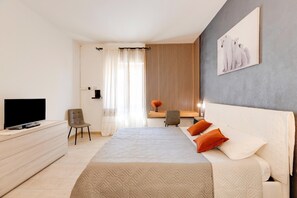 Ein modernes Hotelzimmer mit Bett, Fernseher, Schreibtisch und Stuhl.