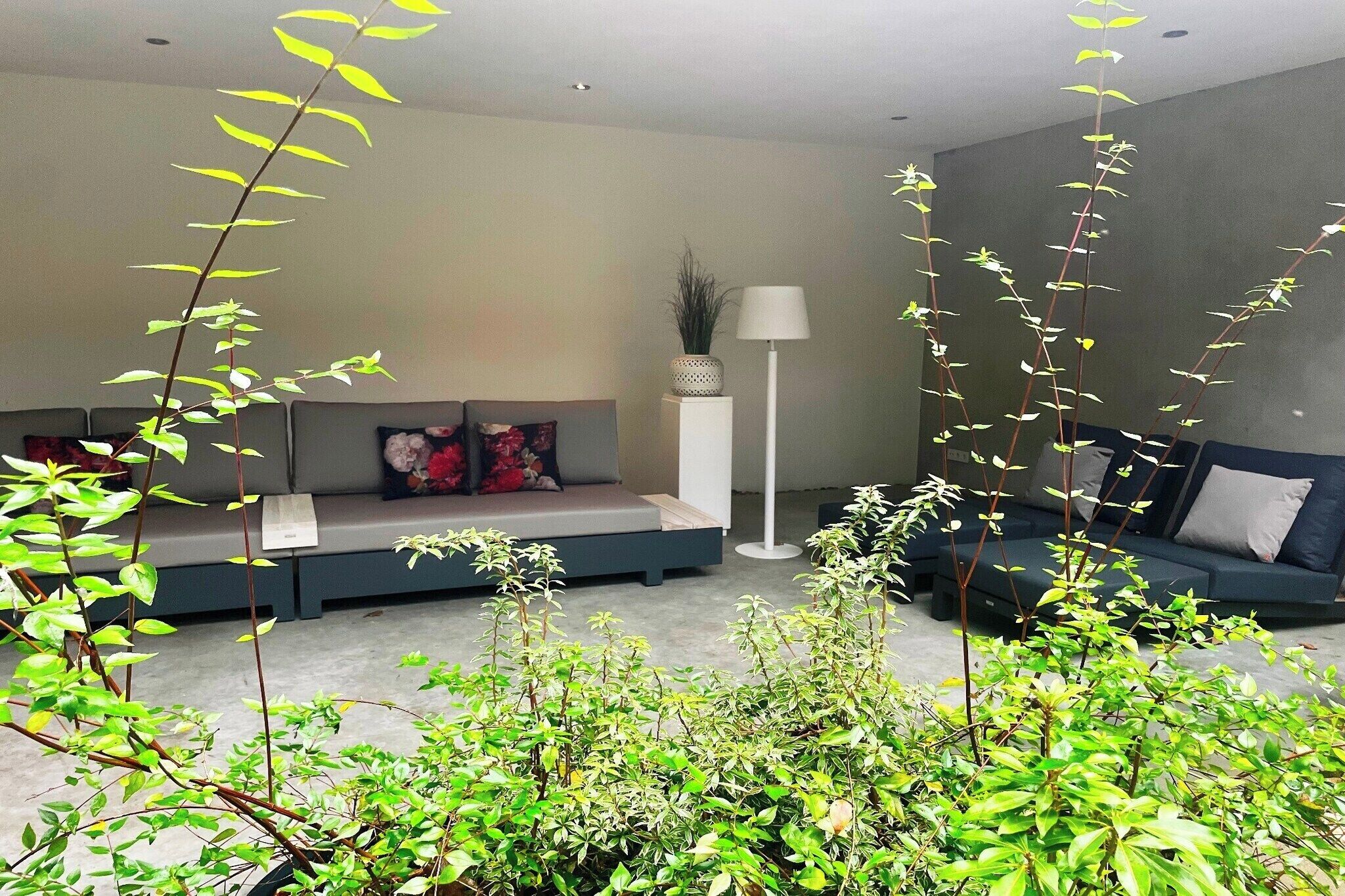 Un salon moderne avec un canapé, une lampe sur pied et des plantes d’intérieur.